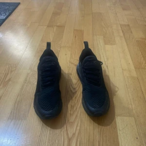 Svarta Nike Air Max sneakers - Säljer ett par helsvarta Nike Air Max sneakers med snörning och rund tå. Skorna har en synlig luftbubbla i sulan och är tillverkade i syntetmaterial med mesh-detaljer för extra andningsförmåga. Perfekta för dig som gillar sportig stil. knappt använd haft i 2 månader 