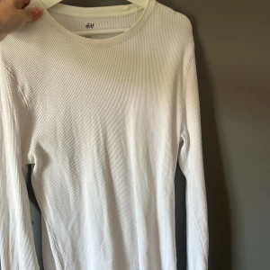 Vit ribbad långärmad tröja från H&M - Säljer en enkel och stilren vit långärmad tröja från H&M. Tröjan är ribbad och har en rund halsringning. Perfekt basplagg att ha i garderoben.