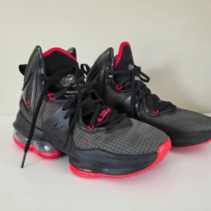 Svarta och röda Nike LeBron basketskor - Nike LeBron basketskor. Skorna har snörning, mesh-överdel och LeBron-logga på baksidan. Perfekta för dig som gillar basket eller vill sticka ut med sportig stil. Mycket bra skick, endast använda ett par gånger.