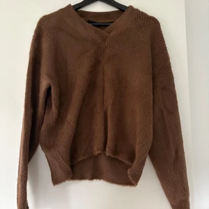 Brun fluffig tröja  - Mysig brun långärmad tröja från KappAhl i fluffigt material. Tröjan har v-ringad hals och en lös passform, perfekt för kyliga dagar. Enkel design utan mönster eller extra detaljer.
