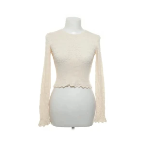 Vit spetsstickad topp från Zara - Supersöt vit topp från Zara med lång ärm och spetsstickat mönster. Modellen är croppad med vågig kant nertill och har en tajt passform. Köpt på sellpy men aldrig använd pga för liten💘💘