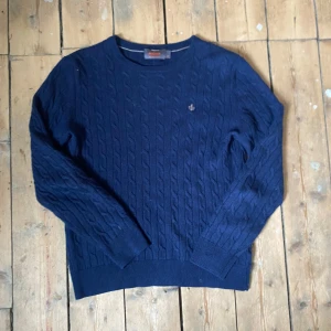  kabelstickad merino ull tröja från Morris - Säljer en marinblå kabelstickad tröja från Morris i 100% merinoull. Tröjan har rund halsringning, långa ärmar och en liten broderad logga på bröstet. Perfekt för kyligare dagar och enkel att matcha med olika outfits. Obs sitter som S!
