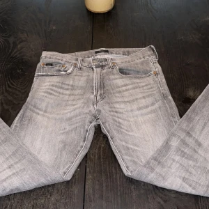 Grå jeans från Polo nypris 2500kr köpta från Nk - Snygga grå jeans från Polo med en klassisk femficksdesign. De har en knappgylf och bälteshällor, vilket gör dem perfekta för en avslappnad stil. Jeansen har en lätt tvättad look som ger dem en trendig touch.