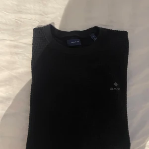 Svart stickad tröja från GANT - Säljer en svart stickad tröja från GANT i storlek S. Tröjan har rund halsringning och diskret GANT-logga på bröstet. Oanvänd!