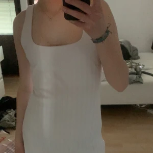 Vit ribbad ärmlös klänning - Säljer en vit, ärmlös klänning med ribbad struktur. Klänningen har en rak passform och är vadlång. Från Zara. Aldrig använt.