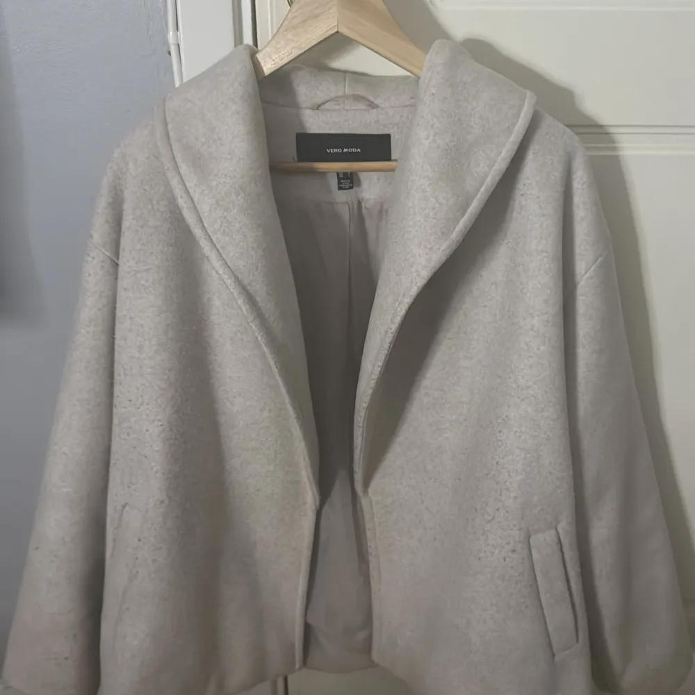Säljer en stilren beige kappa från Vero Moda med bred krage och fickor på sidorna. Jackan har en mjuk ullblandning och är perfekt för höst och vår. Enkel och tidlös design som passar till många outfits.. Takit.