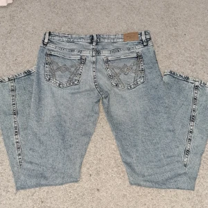 Ljusblå bootcut jeans med broderade bakfickor - Säljer ett par ljusblå jeans med bootcut passform och snygga broderade detaljer på bakfickorna. Jeansen har klassisk femficksdesign och normalhög midja. Perfekta för en avslappnad och trendig look.