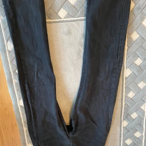 Svarta Levi's 501 jeans W30 L32 - Klassiska svarta Levi's 501 jeans med raka ben och knappgylf. Jeansen har fem fickor och är tillverkade i ett robust denimtyg. Perfekta för dig som gillar tidlös stil och vill ha ett par jeans som funkar till det mesta.