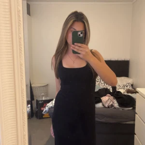 Svart långklänning med breda axelband - En stilren svart långklänning med breda axelband och rak passform. Den är fin men har två av dom