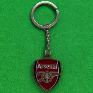 Arsenal nyckelring med klubbmärke - Säljer en snygg nyckelring med Arsenals klassiska klubbmärke i rött, silver och svart. Perfekt accessoar för alla fotbollsfans som vill visa sitt stöd för laget. Metallring och emaljerad logga.