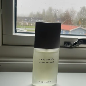 L'Eau d'Issey Pour Homme Eau de Toilette - Fräsch och tidlös herrparfym från Issey Miyake. Flaskan är frostad glas med svart lock och minimalistisk design. Doften är en klassiker med citrus, trä och kryddiga inslag. Volym: 75 ml.