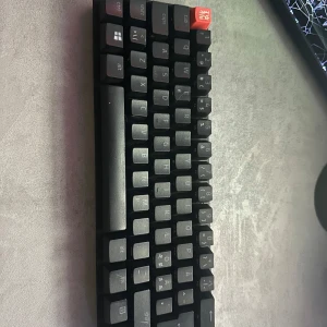 Razer Huntsman Mini mekaniskt tangentbord - Säljer ett kompakt Razer Huntsman Mini tangentbord med svart design och röda detaljer. Tangentbordet har mekaniska switchar och är perfekt för gaming eller skrivbordsarbete där du vill spara plats. USB-anslutning och RGB-belysning.