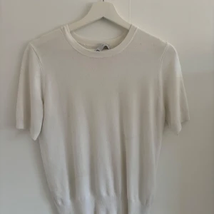 Vit kortärmad tröja från Zara - Säljer en enkel och stilren vit tröja från Zara. Tröjan har korta ärmar och rund halsringning, perfekt för en clean och klassisk look. Materialet känns mjukt och passar bra till många outfits.