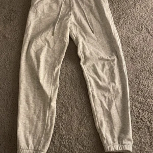 Ljusgrå mjukisbyxor - Säljer ett par ljusgrå mjukisbyxor med resår i midjan och benslut samt dragsko i midjan. Perfekta för chill eller träning. Mjukt och bekvämt material.