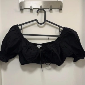 Svart croppad bolerotopp från Chiquelle - Säljer en svart croppad bolerotopp från Chiquelle med puffiga korta ärmar och knytning framtill. Toppen har en söt och trendig design som passar perfekt till sommaren.