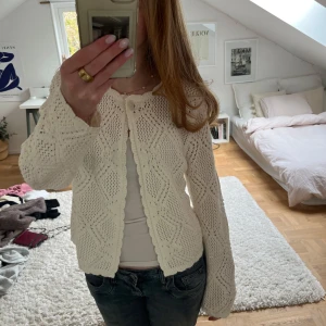 Vit virkad kofta från Lindex - Säljer en söt krämvit stickad kofta från Lindex med fint hålmönster och rund hals. Koftan har långa ärmar och knäpps framtill med en knapp. Andvänd enstaka gånger. Nypris 399kr