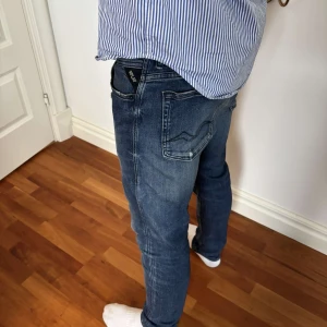 Mörkblå jeansbyxor från Replay - Säljer ett par mörkblå jeansbyxor från Replay med klassisk femficksdesign och diskreta slitningar. Byxorna har normal passform och raka ben. Perfekta till vardags för en stilren look.