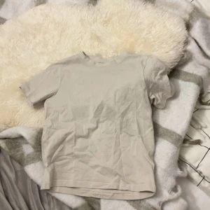 Beige t-shirt från 157 - Säljer en basic beige t-shirt från 157 i 100% bomull. T-shirten har rund halsringning och korta ärmar, perfekt för en enkel och clean look. Passar dig som gillar minimalistisk stil.