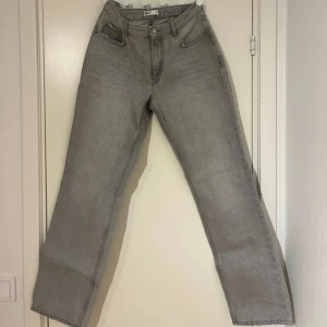 Grå raka jeans från Gina Tricot - Säljer ett par grå jeans från Gina Tricot med raka ben och klassisk femficksdesign. Jeansen har hög midja och stängs med knapp och dragkedja. Perfekta för en avslappnad och stilren look. Lite skitiga där nere vid skon!!