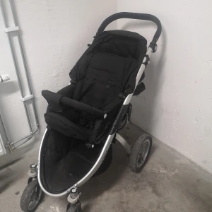 Svart barnvagn med aluminiumram - Säljer en svart barnvagn från baby travel med robust aluminiumram och tre hjul. Vagnen har justerbart ryggstöd, säkerhetsbygel och stor sufflett. Passar för promenader i stadsmiljö och har svängbara framhjul för smidig manövrering.
