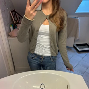 Beige kofta från By Malene Birger - Säljer en klassisk beige kofta från By Malene Birger. Koftan har rund halsringning, knappar framtill och ribbade muddar vid ärmslut och nederkant. Perfekt att slänga över en topp eller t-shirt och passar till det mesta! 