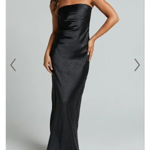 Svart axelbandslös långklänning - Säljer en elegant svart axelbandslös långklänning i satin med öppen rygg. Perfekt till bal. Aldrig använd