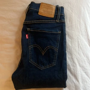 Mörkblå Mile High Super Skinny jeans från Levi's - Säljer ett par mörkblå Levi's Mile High Super Skinny jeans med klassisk femficksdesign och kontrastsömmar. Hög midja och stretchig passform. Oanvända 