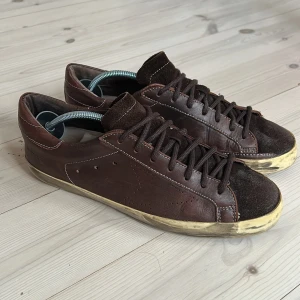 Golden Goose superstar - Ett par snygga golden goose super star med en otroligt diskret design. Skorna är i otroligt bra skick med typ inget slitage på sulan. Loggan på plösen har gnuggats bort av sko snörena, kan ses på sista bilden på det guldiga. Har tyvärr ingen låda kvar till skorna.