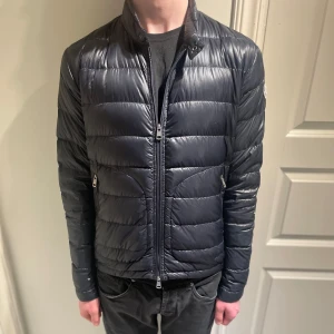 Moncler jacka - Hej! Säljer nu denna Moncler jacka. Garanterad äkthet! Storlek 2 vilket motsvarar S/M. Modellen på bilden är 188. Finns tecken på användning, bland annat mindre hål. Enkelt att laga. Hör av dig vid frågor eller funderingar!