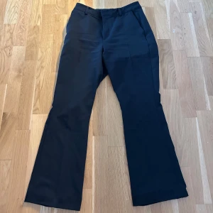 Svarta kostymbyxor från BikBok - Klassiska svarta kostymbyxor från BikBok med normal passform och raka/bootcut ben. Byxorna har hällor för bälte och stängs med dragkedja och knapp. Perfekta för en stilren look. Säljer de då jag inte fått någon användning för dem och dessutom är dem för stora