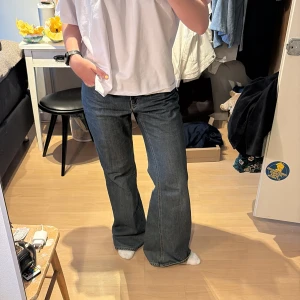 Blå vida jeans - Säljer ett par blå bootcut jeans med snygga nitar på bakfickorna. Jeansen har normal passform och klassisk femficksdesign. Perfekta för dig som vill ha en cool och avslappnad stil.
