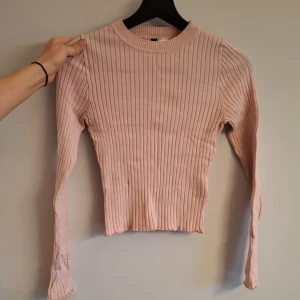 Ljusrosa ribbad tröja från Divided - Säljer en ljusrosa ribbad tröja från Divided. Tröjan har lång ärm, rund halsringning och är figurnära i modellen. Perfekt för dig som gillar en enkel men snygg stil.