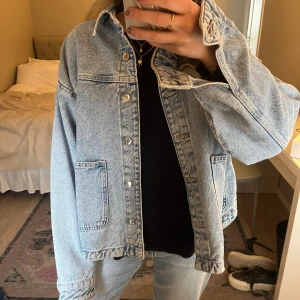 Ljusblå jeansjacka från Zara - Säljer en klassisk ljusblå jeansjacka från Zara med två stora fickor framtill och silverfärgade knappar. Jackan har en rak passform och är perfekt att nu i sommar!