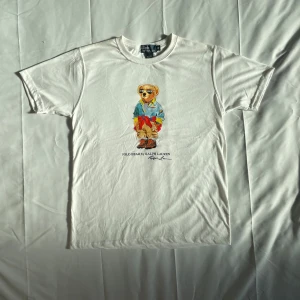 Polo Bear - Polo Ralph Lauren Polo Bear T-shirt – Vit – M Klassisk t-shirt med ikoniska Polo Bear. Stilren, bekväm och perfekt för både vardag och streetwear. 🔹 Storlek M 🔹 Färg: Vit 🔹 100 % bomull 🔹 Mycket fint skick – inga fläckar eller hål.  📦 Snabb leverans 📩 Hör av dig vid frågor!  #PoloBear #RalphLauren #Streetwear #Herrmode #StorlekM #VintageStil #PoloRalphLauren 