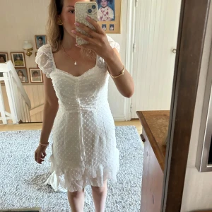 student klänning - Säljer en söt vit klänning med prickigt mönster och volangdetaljer. Klänningen har korta ärmar och en v-ringad design. Perfekt för sommarens alla tillfällen!  (Köpt på plick pch därför inte mina bilder 🩷)