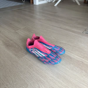 Adidas X F50 lace less - Säljer ett par Adidas F50 i blått och rosa med vita detaljer. Skorna är utan snörning. Storlek 44 och är i mycket bra skick eftersom att de ej är så använda.