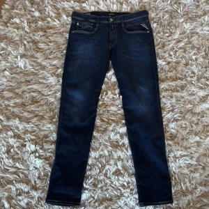 Replay Anbass 33/32  - Snygga mörkblå jeans från Replay i modellen Anbass. De har en slim fit och klassisk femficksdesign med snygga detaljer på bakfickorna. Perfekta för en stilren look.