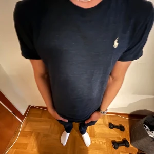 Mörkblå t-shirt från Ralph Lauren - Snygg mörkblå t-shirt från Ralph Lauren med klassisk passform och korta ärmar. Ikoniska Polo-loggan broderad i vitt på bröstet. Tillverkad i mjuk bomull som känns skön mot huden. Perfekt till jeans eller shorts för en clean look. Storlek S. 