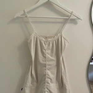 Vit linnetopp  - Supersöt vit linnetopp med smala axelband och fin virkad spetskant vid urringningen. Toppen är perfekt för varma sommar dagar. Mjuk och skön i bomullsmaterial. Perfekt att styla med jeans eller kjol. Toppen är för stort för mig så den är knappt använd. Super duper söt topp att har denna sommar och vid köpet av denna topp kan du få ett litet klistermärke! 