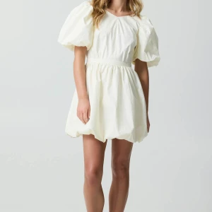 Ljusgul kort klänning med puffärm och rosett - Supersöt ljusgul kortklänning med puffiga ärmar och markerad midja. Klänningen har öppen rygg med stor rosett och v-ringning bak. Tillverkad i ett lätt bomullstyg som känns luftigt och fräscht. Perfekt för sommarens alla tillfällen! Säljer klänningen då den ej kommit till användning ännu och har en liknande! 💓💐☀️storlek XS, passar S också! Nytt skick med prislapp på. 