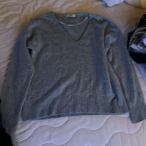 Grå v-ringad stickad tröja JDY - Mysig grå stickad tröja från JDY med v-ringning och långa ärmar. Tröjan är jätte skön och mysig. Enkel och stilren design som funkar till det mesta.