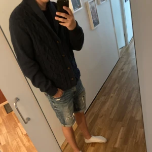 Mörkblå stickad kofta med knappar - Säljer en mörkblå stickad kofta med snyggt mönster och knappar framtill. Koftan har en bred krage och långa ärmar, perfekt för lager-på-lager. Passar dig som gillar en klassisk men chill stil. Den passar S/M