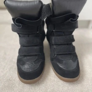 Isabel marant skor - Snygga svarta sneakers med tre breda kardborreband och högre skaft. Skorna har en brun gummisula och är tillverkade i en mix av mocka och syntet. Perfekta för dig som gillar en sportig och trendig look. Helt okay sick därav priset går även int ner pris!❤️sulorna sitter sådär på och den ena är limmad som inte syns på bilden, köpt på Plick och aldrig nästan använt