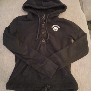 Mörkblå hoodie från Hollister - Mysig mörkblå hoodie från Hollister med broderad logga på bröstet. Tröjan har huva med snörning, knappar framtill och känguruficka. Perfekt för kyliga dagar och enkel att matcha med jeans eller shorts. Köpt på en second hand för ett bra tag sen men har bara använt 2-3 gånger själv🥲 om du har frågor eller funderingar är det bara att skriva❤️