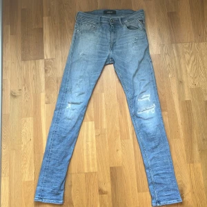 Replay ljusblå  jeans herr W30 L32  - Säljer ett par ljusblå slim jeans från Replay med slitna detaljer och klassisk femficksdesign. Jeansen har normal midja och smal passform hela vägen ner. Perfekta för dig som gillar en modern och avslappnad look. Dom har även en fläck på höger ben men inget som syns tydligt.