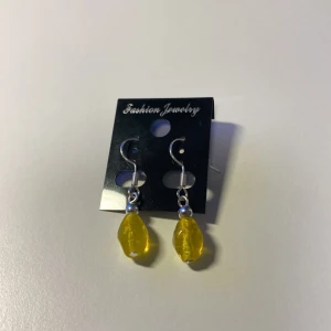 Handformade Gula örhängen med droppformad pärla *Endast 1 Kvar* - Snygga örhängen från Fashion Jewelry med droppformade, facetterade pärlor i klar gul färg och silvriga detaljer. Perfekta för att ge din look en färgklick och lite extra glow. Hängande modell med krokfäste.