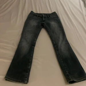 Bootcut jeans från Caltex, storlek 32 - Snygga mörkblå bootcut jeans från Caltex i klassisk denim. Jeansen har en lätt tvättad look, fem fickor och orangea sömmar. Perfekt för dig som gillar en retro vibe och vill ha ett par jeans med lite vidare ben nertill.