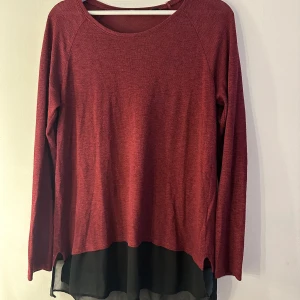 Vinröd långärmad tröja med svart chiffong - Vinröd långärmad tröja från MyWear Woman i mjukt material med svart chiffongdetalj nedtill. Tröjan har rund halsringning och en loose passform som ger en avslappnad vibe. Perfekt för dig som gillar lager-på-lager-look och vill ha något snyggt men bekvämt. Storlek M