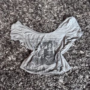 Grå croppad topp med anime-tryck - Säljer en grå croppad topp från SHEIN med stort anime-inspirerat tryck framtill och japanska tecken. Toppen har bred, rundad halsringning och korta ärmar. Perfekt för dig som gillar edgy och unik streetstyle.