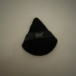 Svart makeup-puff från Glam - En svart makeup-puff från Glam, perfekt för att applicera puder eller fixa basen. Den är droppformad med ett elastiskt band för bra grepp och är gjord i mjukt tygmaterial. Smidig att använda för både ansikte och under ögon.
